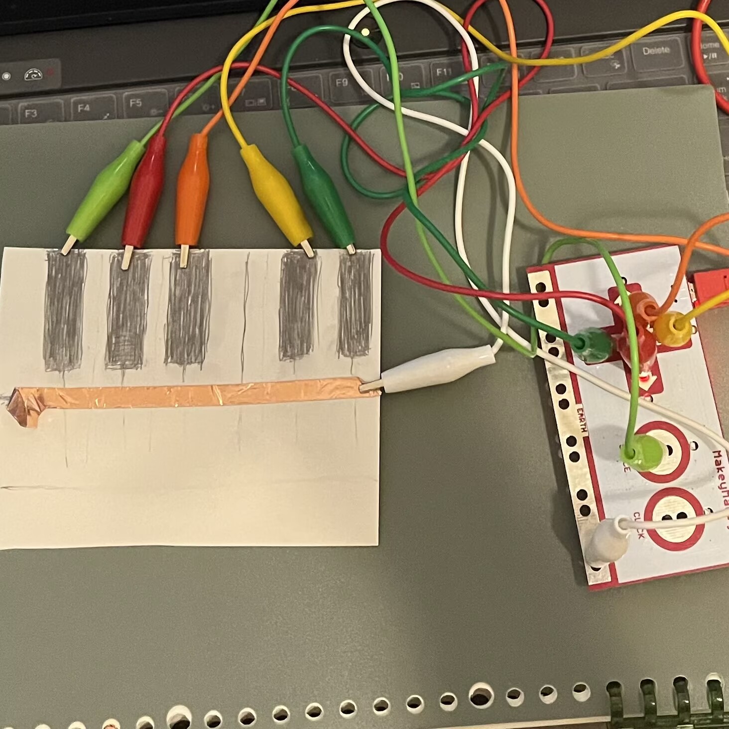 I used a pencil sketch of a piano keyboard for five buttons. I explored the use of different conductive materials. I placed the ground under the keyboard so that a circuit is completed when both a key and the ground are pressed.