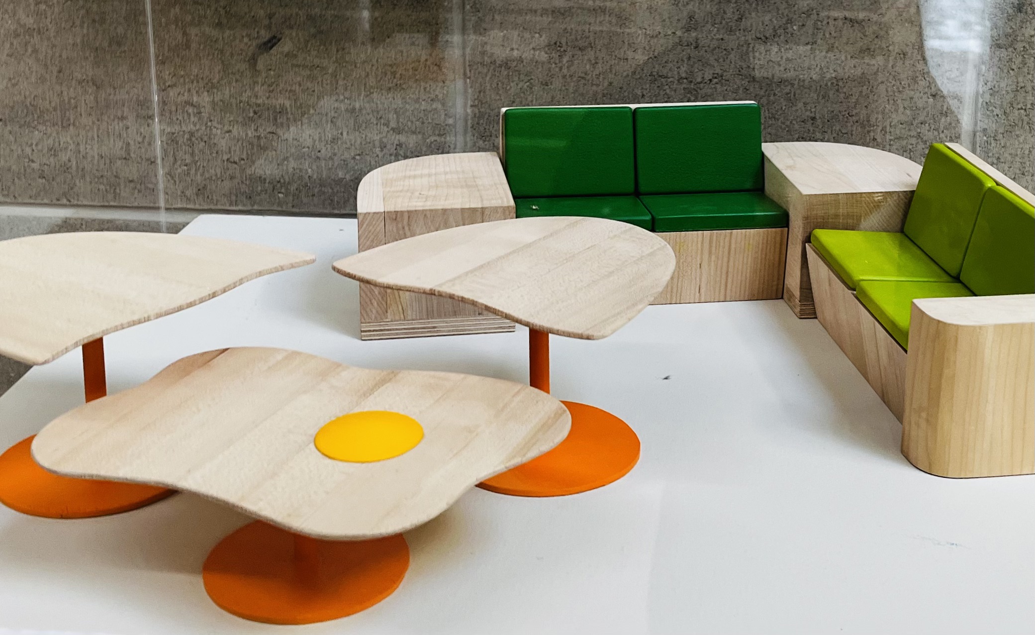This exhibit is a set of furniture models, which is associated with the Craft and Design (furniture) program. Those parts with colors I assume 
      they are made by plastic, because considering those colorful coating and how they're reflect the light. The table surface and couch base are made by wood.