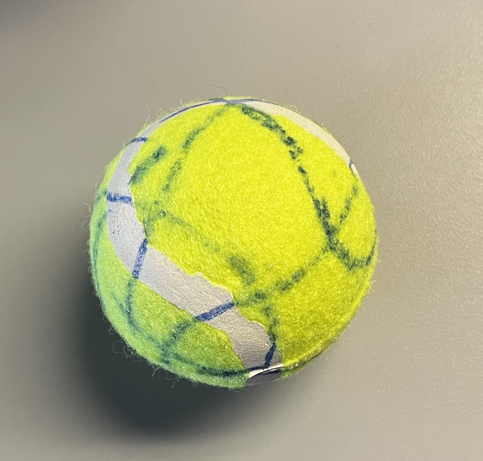 This object is made of textile.
      <br>Color: Yellow-green with white rubber seam 
      <br>Surface Texture: Fuzzy texture, slightly rough.
      <br>Material Plasticity: Semi-ridig, it's hard to bend but still compresses under pressure, elastic rebound. 
      <br>Material State: Refined, the textile is processed for sport use.
      <br>Material Use: Sports equipment, pet toys, DIY crafts.